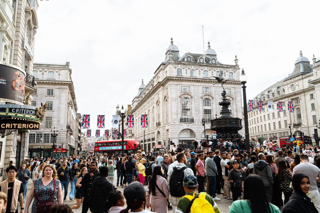 A bustling scene at Piccadilly Circus, London, filled with diverse people and iconic UK elements.