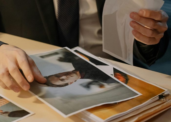 Man in suit analyzing photographs on a desk, suggesting investigation work.